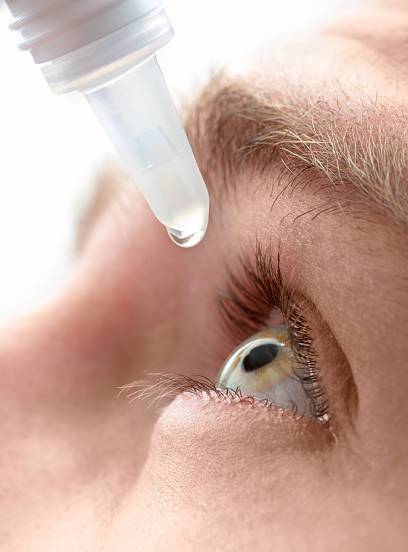 Closeup view of young man applying eye drop